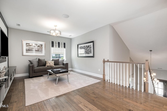 living area with dark wood-style flooring, a chandelier, and baseboards