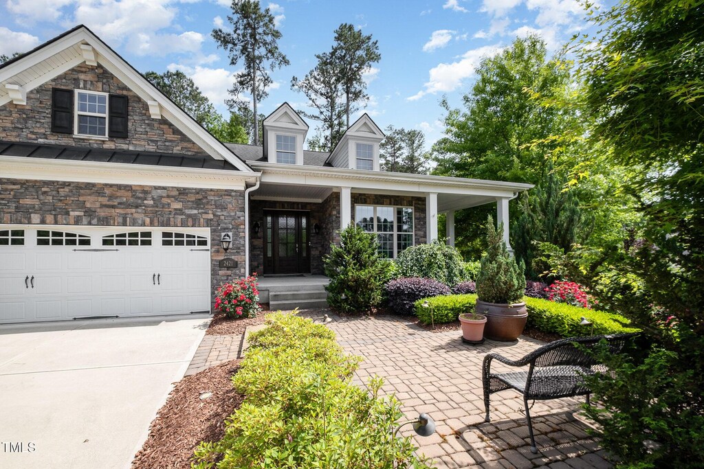2421 Beckwith Rd, Apex, NC 27523 - view of front of property featuring a porch, concrete driveway, an attached garage, and stone siding