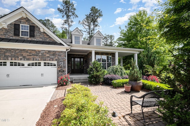 view of front of property featuring a porch, concrete driveway, an attached garage, and stone siding