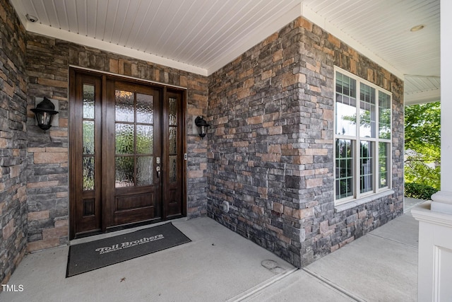 doorway to property featuring covered porch and stone siding