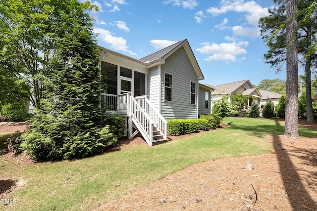 view of side of home with a lawn, stairway, and a sunroom