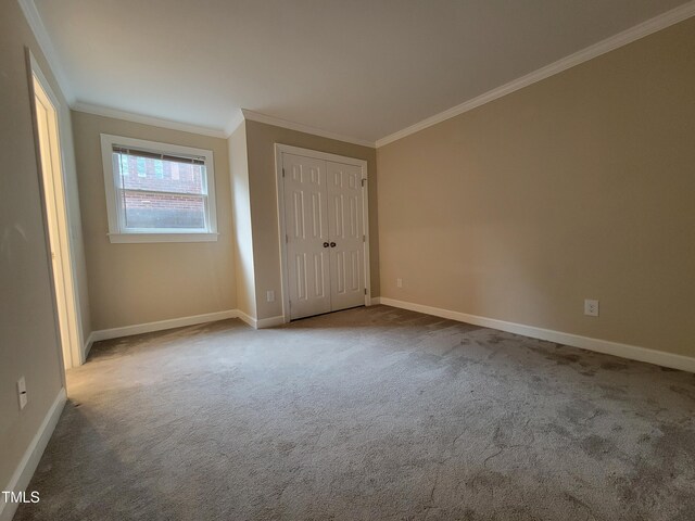 unfurnished bedroom with carpet flooring, crown molding, baseboards, and a closet