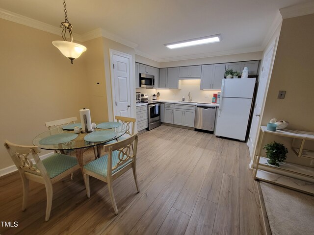 kitchen with stainless steel appliances, a sink, light wood-style flooring, gray cabinetry, and light countertops