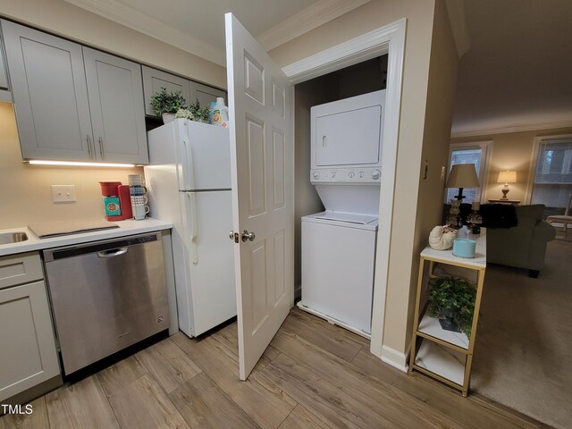 kitchen featuring stainless steel dishwasher, estacked washer and dryer, freestanding refrigerator, crown molding, and light countertops