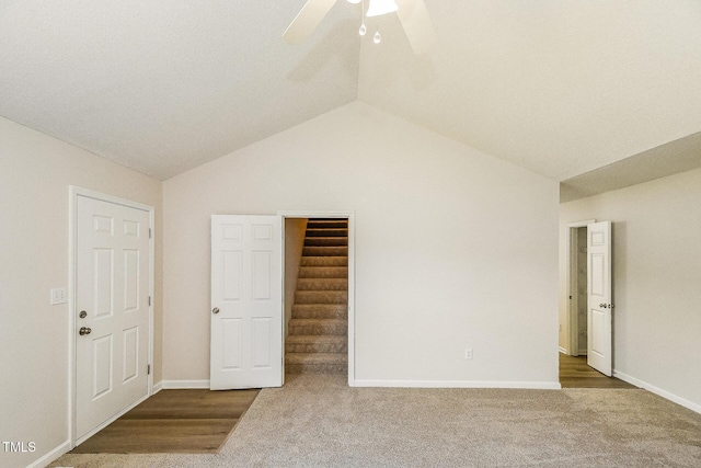 unfurnished bedroom featuring carpet floors, lofted ceiling, baseboards, a ceiling fan, and a walk in closet