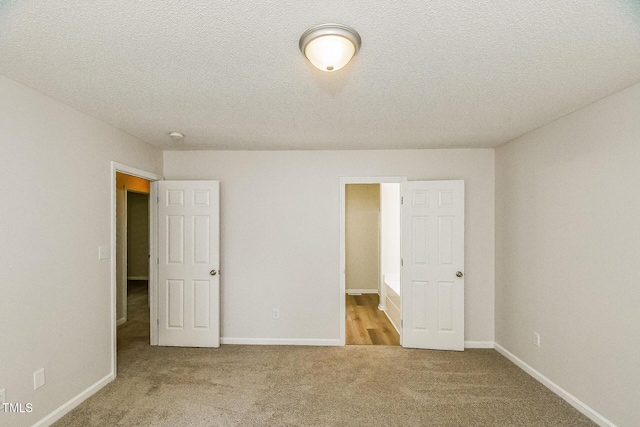 unfurnished bedroom featuring carpet flooring, baseboards, and a textured ceiling
