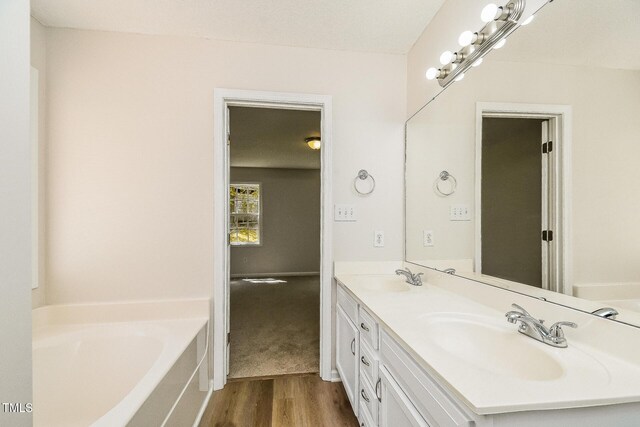 full bathroom with wood finished floors, a bath, and double vanity