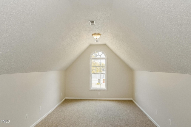 bonus room featuring a textured ceiling, baseboards, vaulted ceiling, and carpet floors