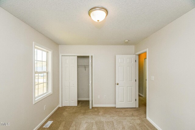 unfurnished bedroom with carpet, a textured ceiling, baseboards, and a closet
