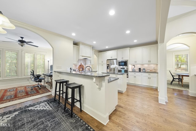 1211 New Grissom Way, Wake Forest, NC 27587 - kitchen with arched walkways, stainless steel appliances, a breakfast bar, a peninsula, and ornamental molding