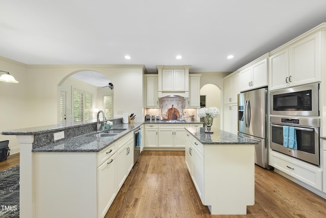 1211 New Grissom Way, Wake Forest, NC 27587 - kitchen featuring stainless steel appliances, a sink, arched walkways, a center island, and recessed lighting