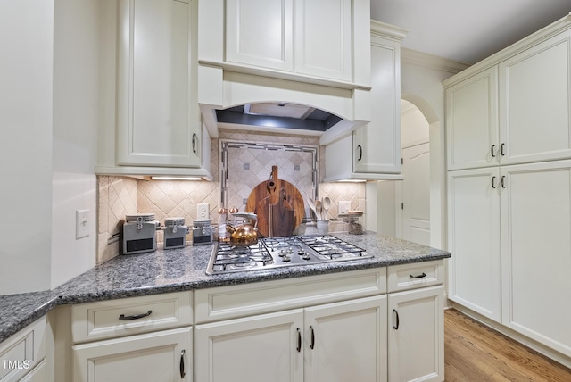 1211 New Grissom Way, Wake Forest, NC 27587 - kitchen featuring stainless steel gas stovetop, backsplash, dark stone counters, light wood-style floors, and arched walkways