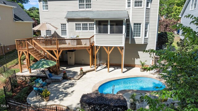 back of house with a sunroom, a patio area, a deck, and fence