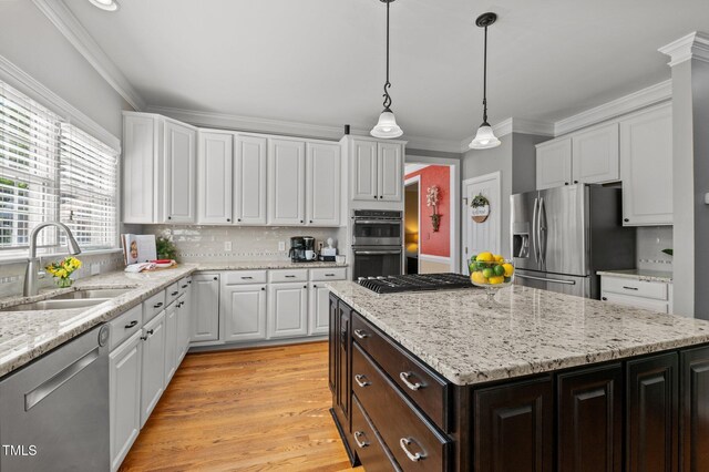 kitchen with stainless steel appliances, a sink, white cabinets, ornamental molding, and dark brown cabinets