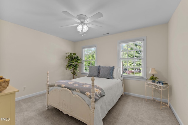 bedroom featuring light colored carpet, baseboards, and a ceiling fan