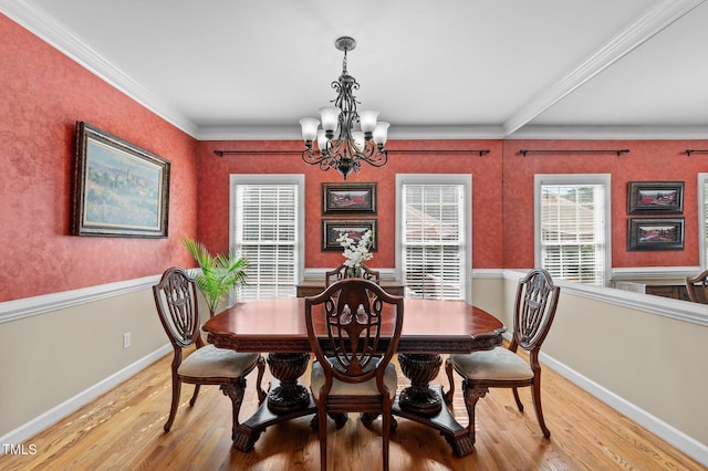 dining space featuring a chandelier, light wood-style flooring, baseboards, and ornamental molding