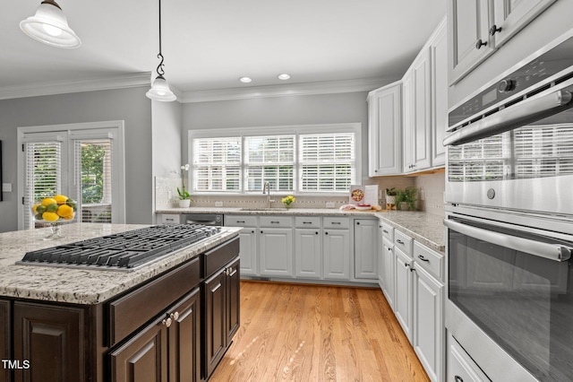 kitchen featuring stainless steel appliances, a sink, white cabinets, dark brown cabinets, and crown molding