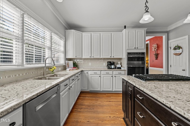 kitchen featuring appliances with stainless steel finishes, a sink, white cabinets, crown molding, and backsplash