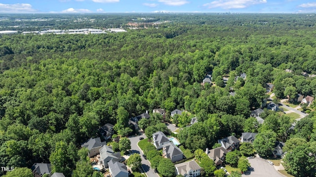 aerial view of property and surrounding area with a heavily wooded area and nearby suburban area