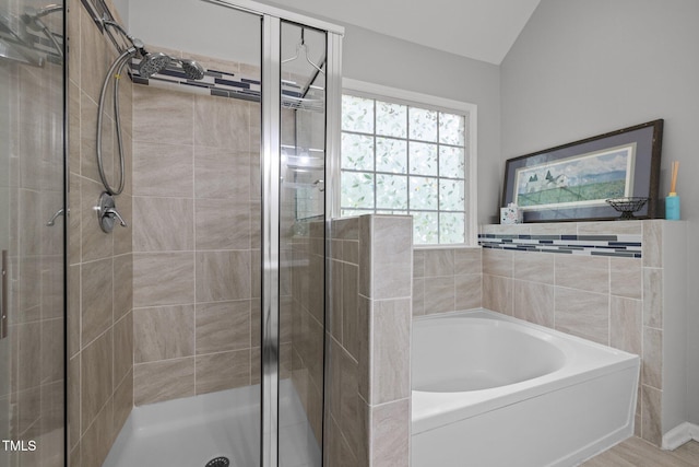full bathroom with a stall shower, a garden tub, and lofted ceiling