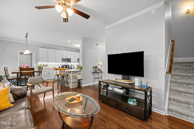 living area featuring ornamental molding, a ceiling fan, baseboards, stairway, and dark wood-style flooring