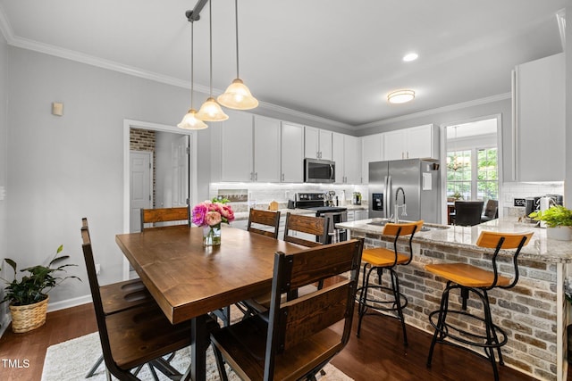 dining area featuring crown molding, dark wood-style flooring, a fireplace, and baseboards