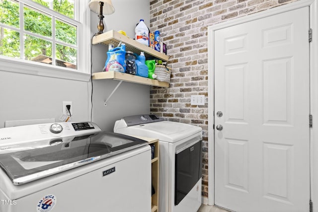 laundry room with brick wall and washer and clothes dryer