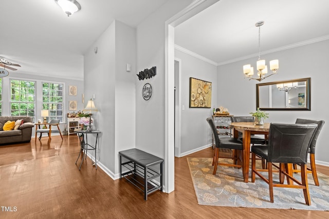 dining space featuring a chandelier, wood finished floors, baseboards, and ornamental molding