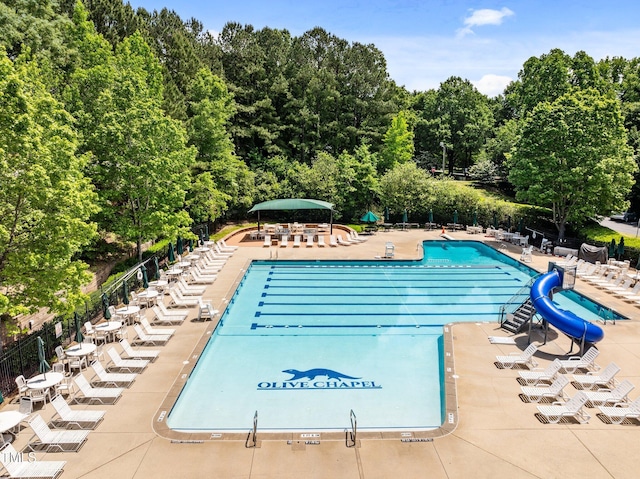 community pool featuring a water slide, a patio, and fence
