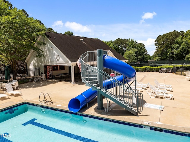 community pool featuring a water slide, fence, and a patio