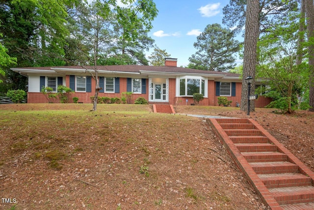 single story home featuring a chimney and brick siding