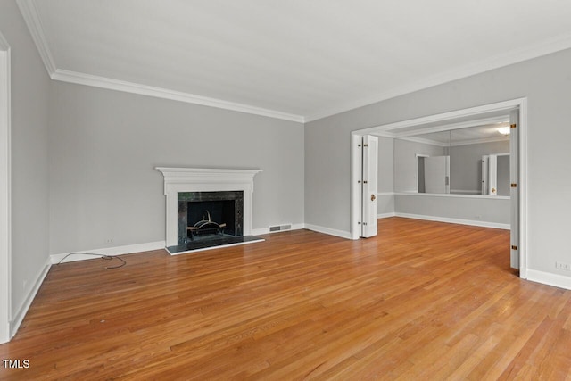 unfurnished living room featuring light wood-style floors, ornamental molding, a high end fireplace, and baseboards