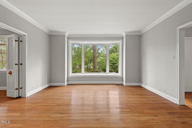 unfurnished room with ornamental molding, baseboards, and light wood-type flooring