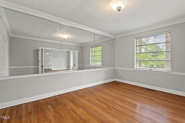 unfurnished room with baseboards, wood finished floors, and ornamental molding