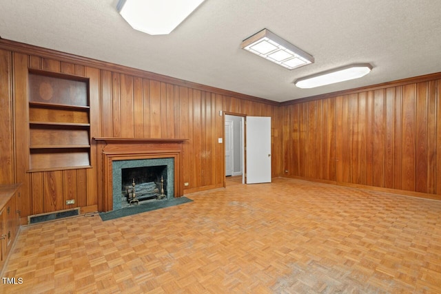 unfurnished living room featuring a textured ceiling, wood walls, a premium fireplace, and baseboards