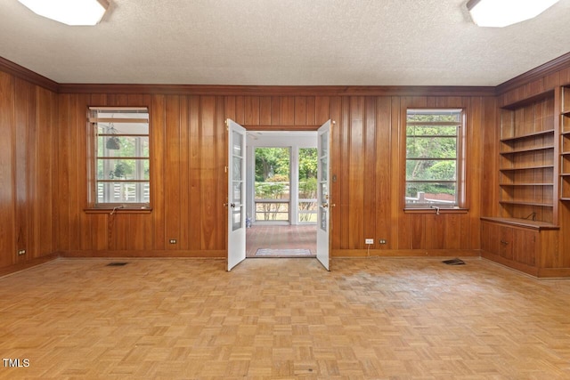 spare room featuring baseboards, wooden walls, a textured ceiling, and ornamental molding