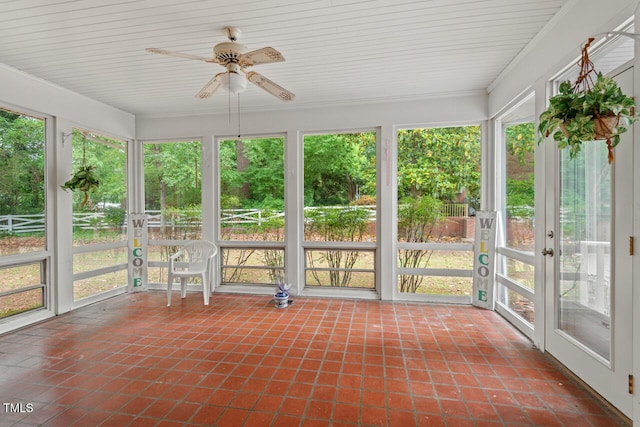 unfurnished sunroom featuring tile patterned floors, a ceiling fan, and healthy amount of natural light