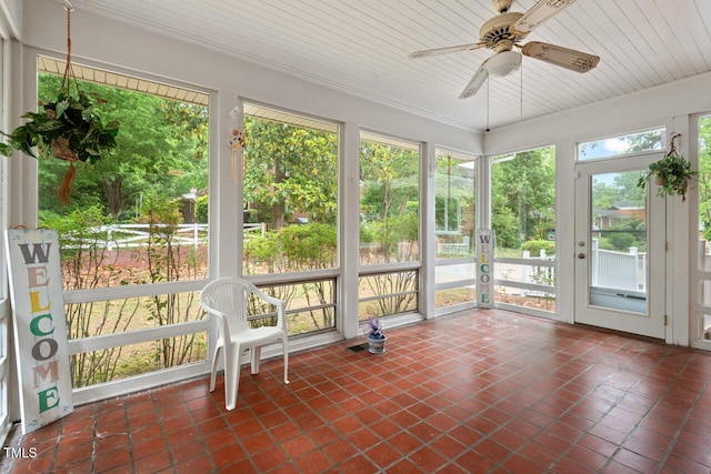 unfurnished sunroom featuring a ceiling fan, tile patterned flooring, plenty of natural light, and wood ceiling