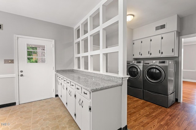 clothes washing area with cabinet space, independent washer and dryer, and light wood-type flooring