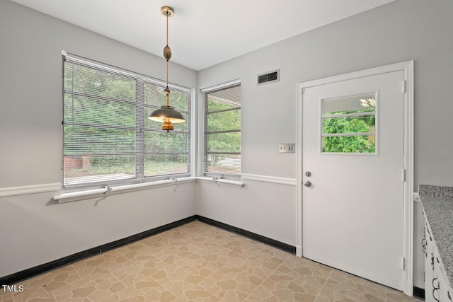 unfurnished dining area with light stone finish flooring and baseboards