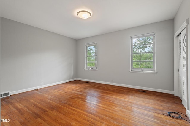 unfurnished bedroom featuring light wood-style flooring, baseboards, and a closet