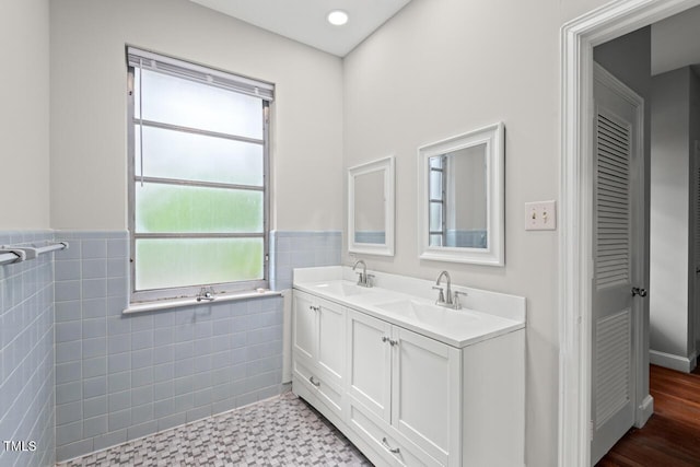 bathroom featuring tile walls, wainscoting, and double vanity