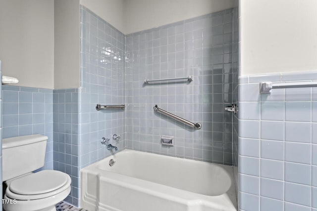 bathroom with tile walls, toilet, and a wainscoted wall
