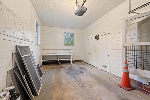 garage featuring a garage door opener and wooden walls