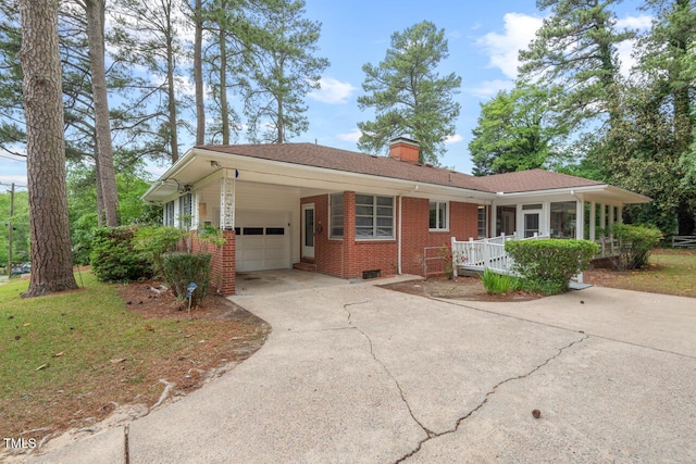 ranch-style house featuring brick siding, driveway, a chimney, a garage, and an attached carport