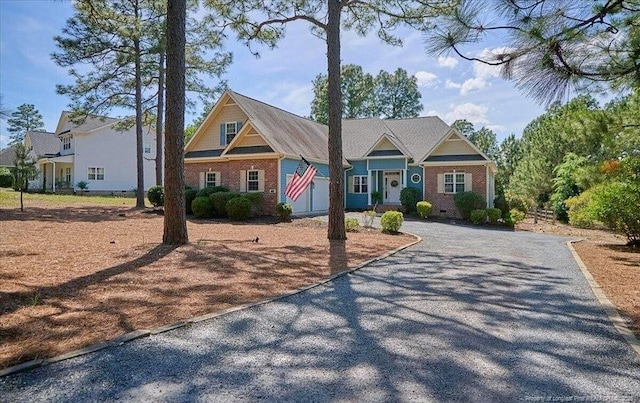 craftsman house with driveway and brick siding