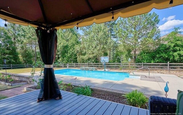 view of pool featuring a fenced backyard, a patio, and view of wooded area