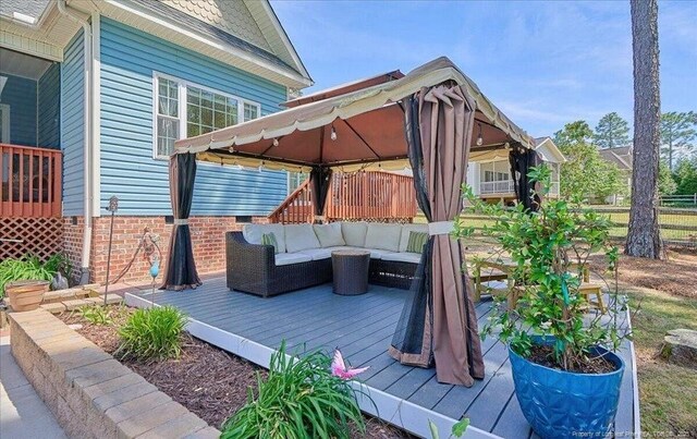 wooden terrace featuring a gazebo and an outdoor living space