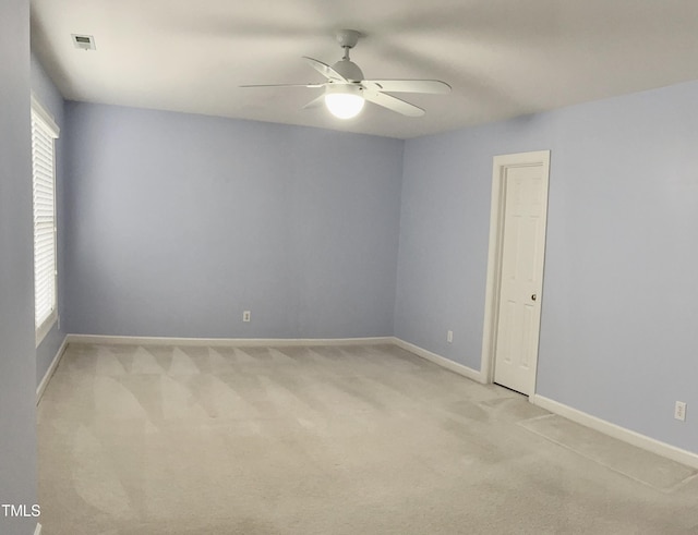 empty room with light carpet, a ceiling fan, and baseboards