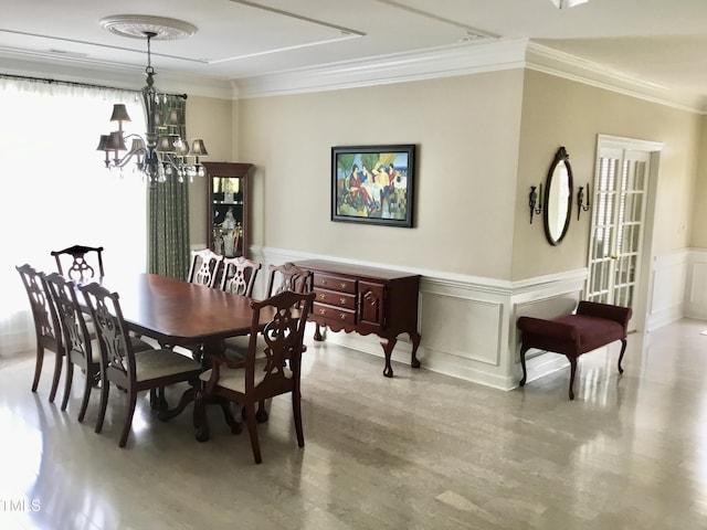dining area featuring ornamental molding, a chandelier, wood finished floors, a decorative wall, and a wainscoted wall